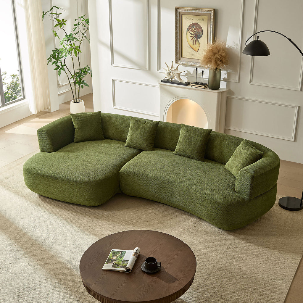 Modern 4-seat curved green sectional sofa in textured fabric with four matching throw pillows, set in a bright room.