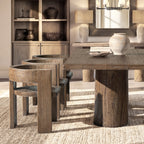 Sculptural dining chair in medium-dark reclaimed elm with a curved back, rustic texture, and modern architectural frame.
