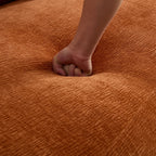 Hand pressing into the seat of the Oversized L-Shape Sofa, emphasizing the deep cushioning and soft, textured fabric.