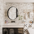Round Black Metal Medicine Cabinet with Mirror installed above a white vanity in a modern bathroom with floral wallpaper.