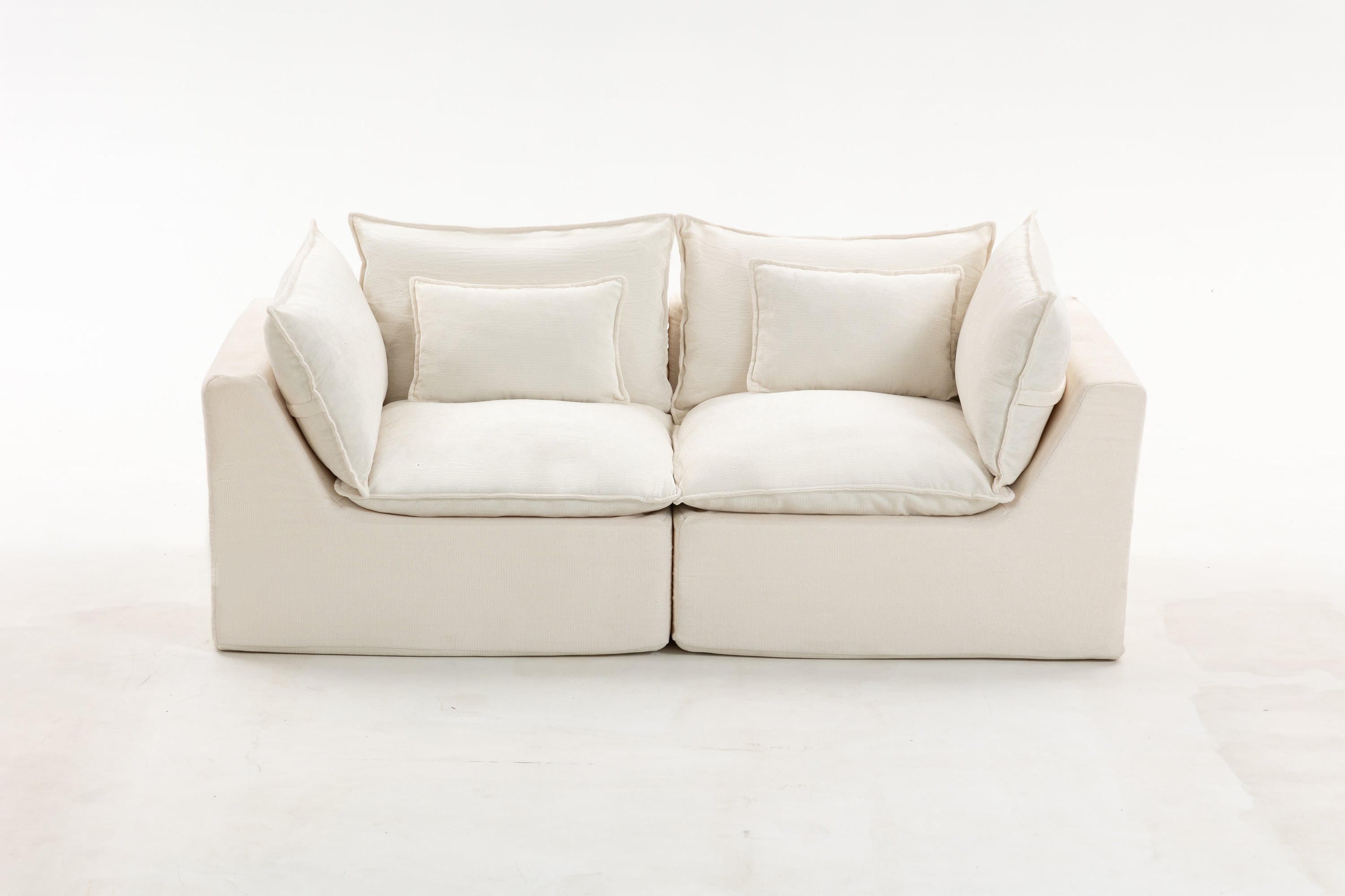 Studio shot of modular sectional sofa in oversized design with cloud-like cushions and soft velvet fabric in neutral cream tone.