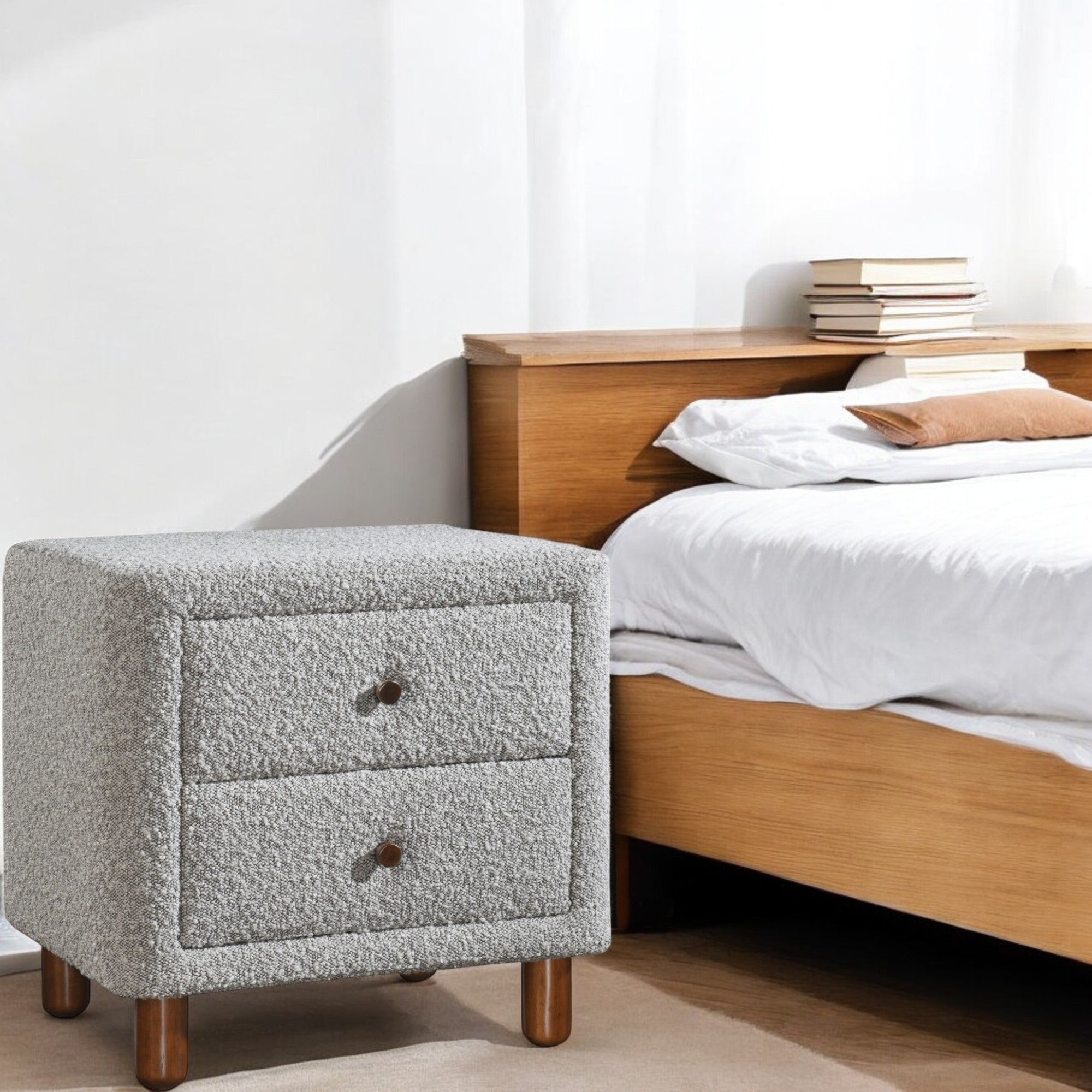 Cleo Gray Boucle Nightstand beside a wooden bed in a modern bedroom. Elegant bedroom furniture with soft boucle texture and wooden legs.