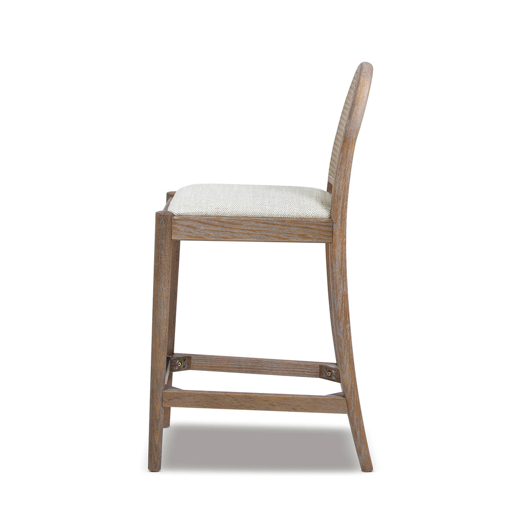 Side profile of Panama 26.5' Rattan Counter Stool with arched cane back and padded seat, highlighting its sleek silhouette and durable wood frame.
