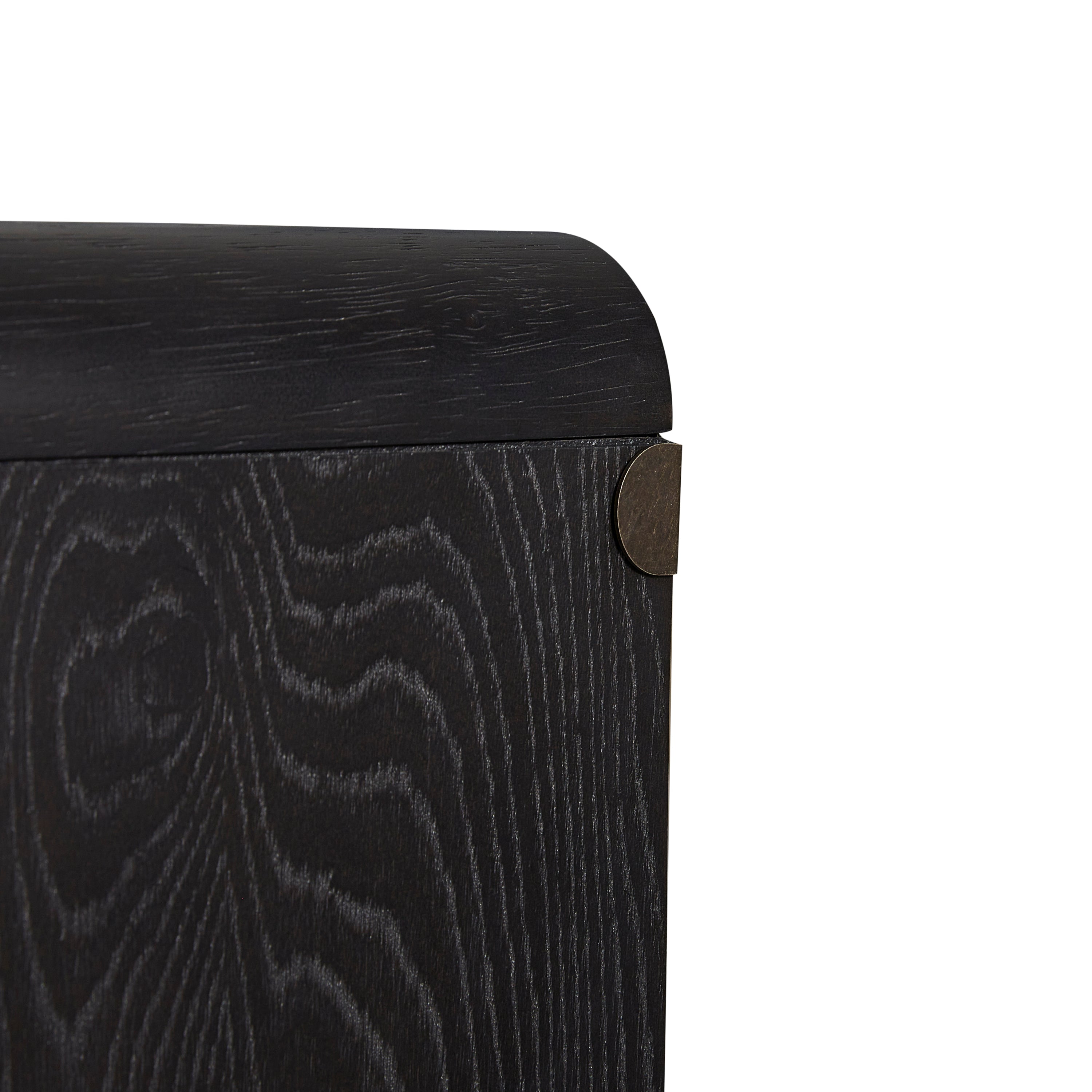 Close-up of Peppercorn Glass Door Server Furniture corner showing textured black wood grain and rounded edge with metal accent.