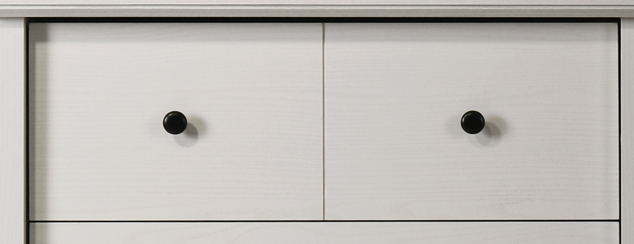 Top drawers of Elara White 4-Drawer Chest featuring round black knobs and subtle wood texture for modern storage.
