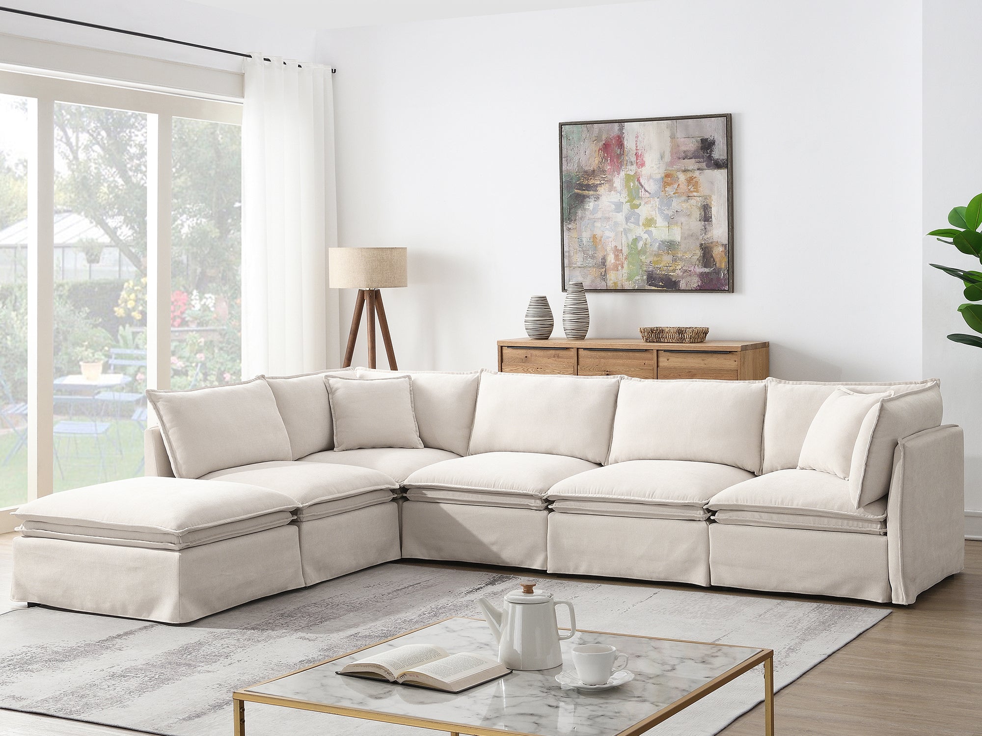 Beige modular sectional sofa with ottoman in a sunlit living room, perfect for family gatherings and customizable seating arrangements.