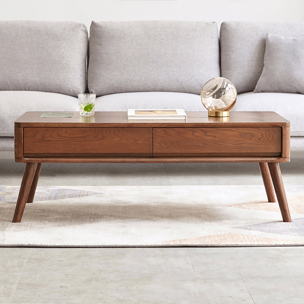 Front view of oak wood lift-top coffee table with closed top and dual drawers, placed in a modern living room.
