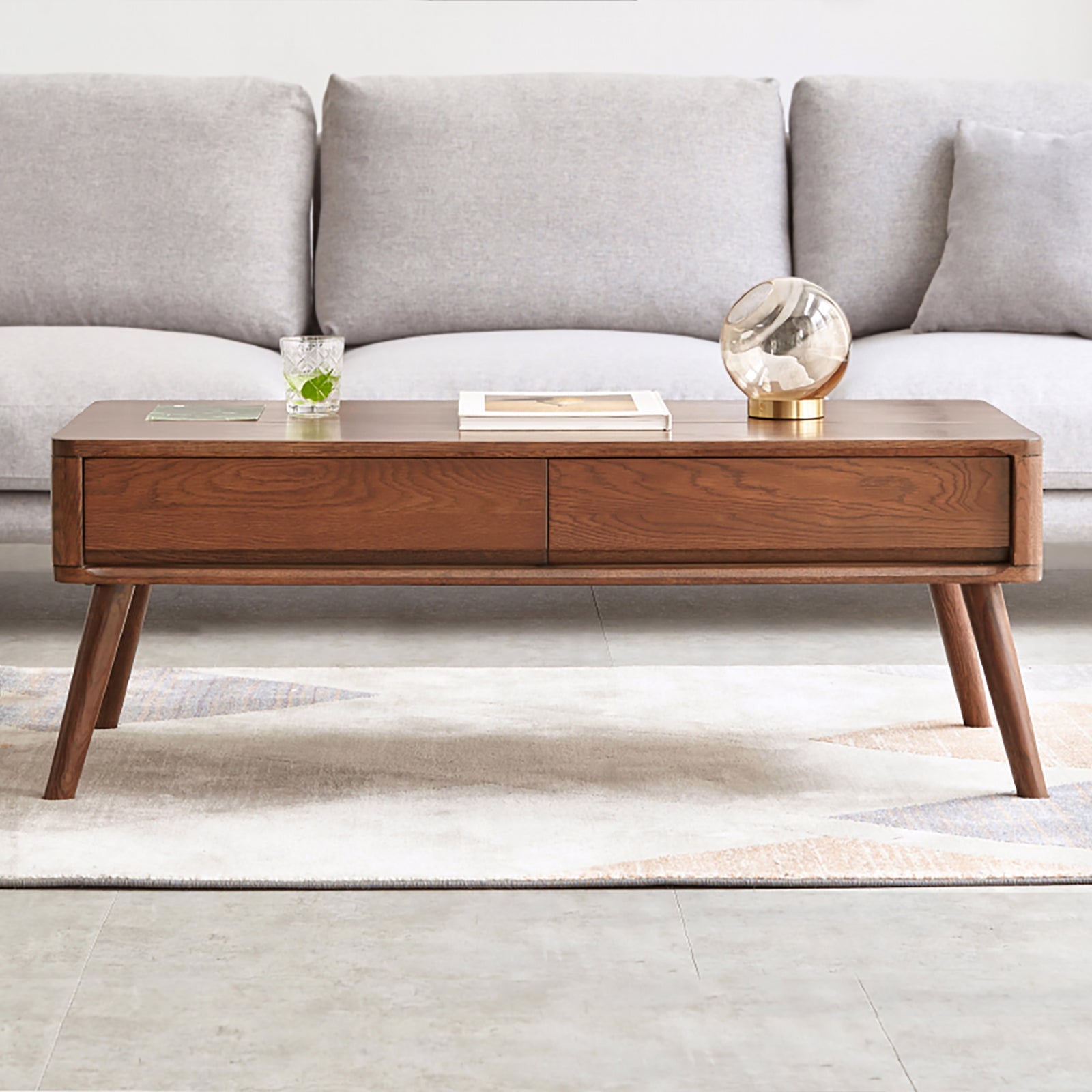 Front view of oak wood lift-top coffee table with closed top and dual drawers, placed in a modern living room.