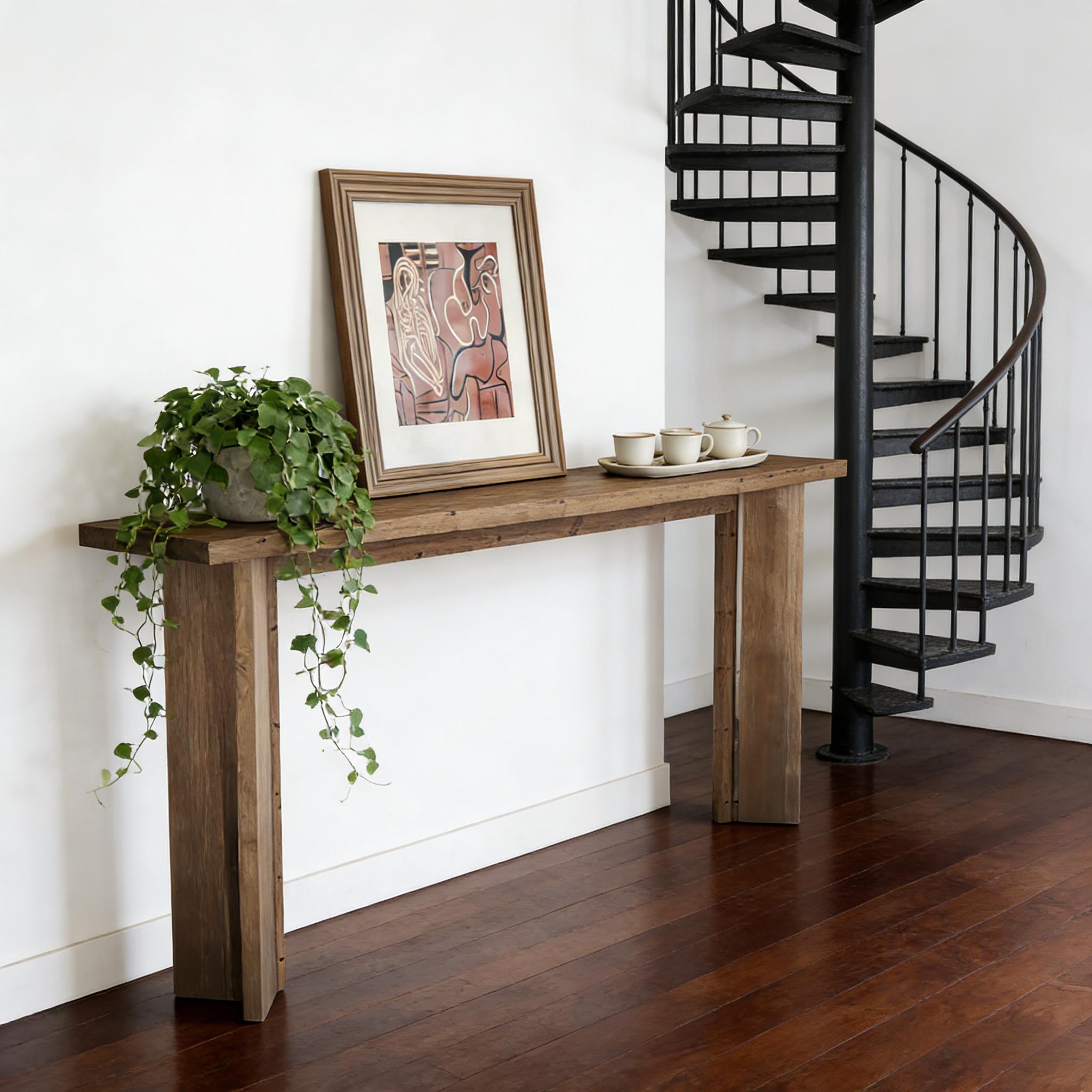 Rustic wooden console table with wide, solid legs, styled with a trailing green plant, framed art, and ceramic tea set.