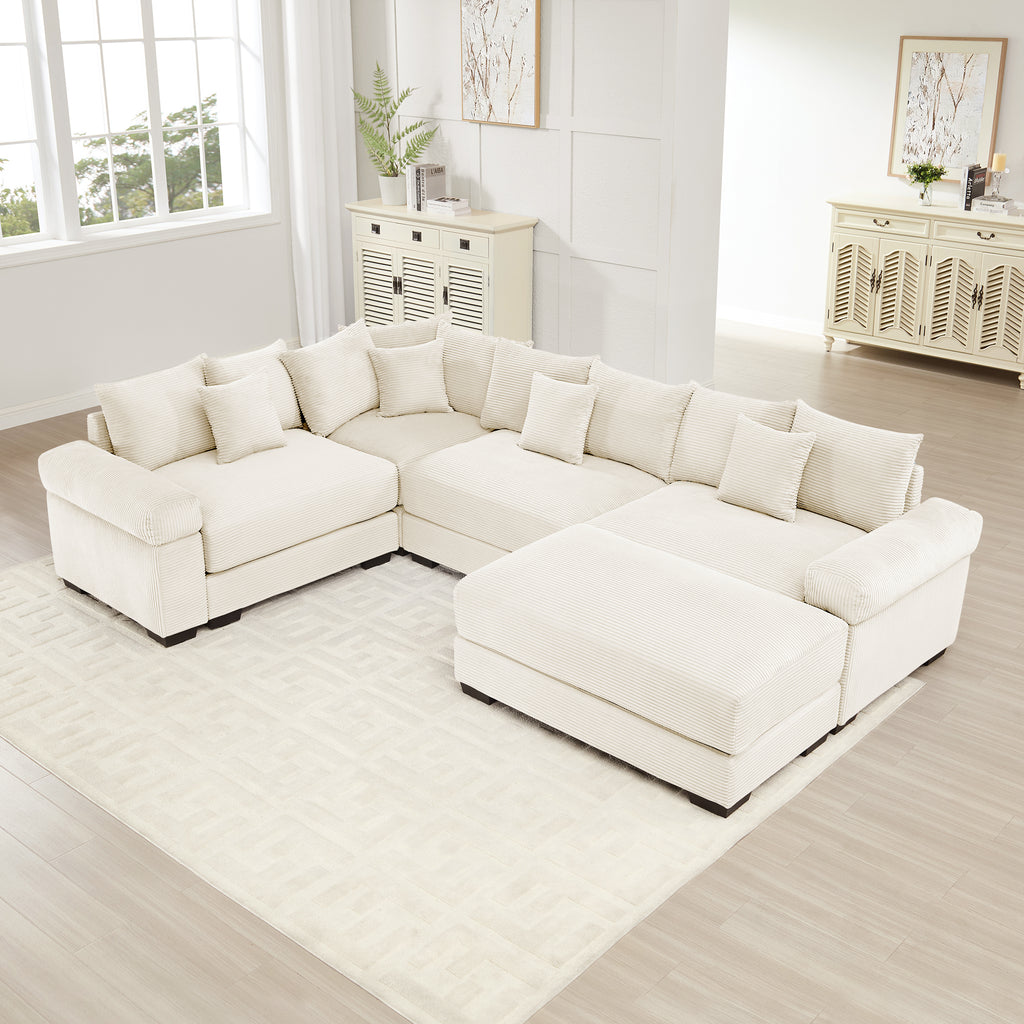 Cream corduroy oversized modular sectional sofa with thick armrests, a large ottoman, and multiple matching throw pillows.