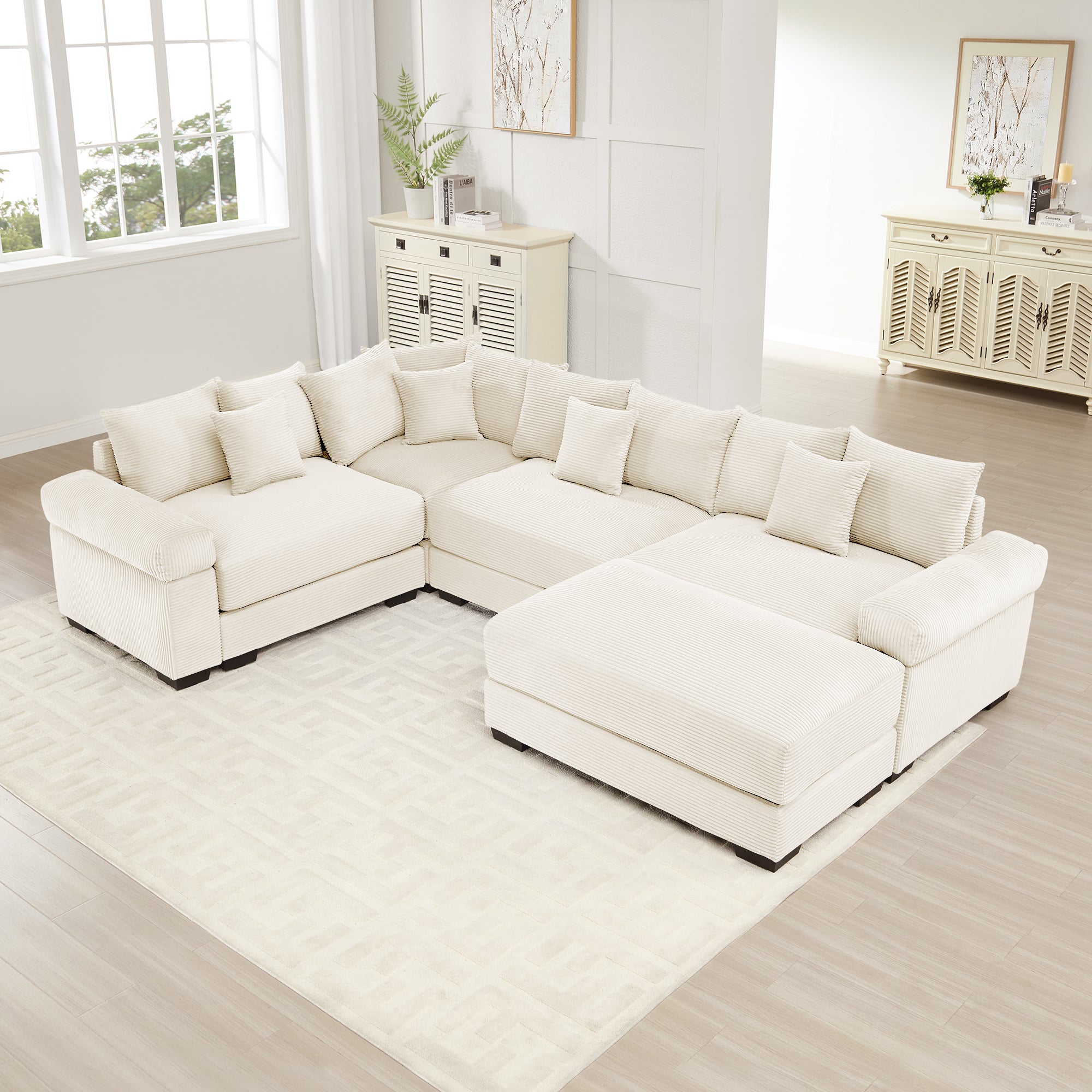 Cream corduroy oversized modular sectional sofa with thick armrests, a large ottoman, and multiple matching throw pillows.