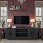 Radiance TV Stand 85 inch TVs - Black Finish styled in a modern living room with wall-mounted TV, lamps, and decorative accents.