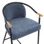 Angled top view of upholstered counter stool showing plush blue seat, curved armrests, and gold-accented black metal frame.