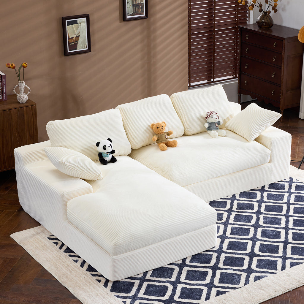 Compressed Corduroy Sofa in white with 3 back cushions and 2 pillows, shown in a cozy living room with plush toys on top.