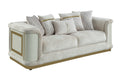 Contemporary beige sofa with gold-accented frame, textured fabric, side panels, and decorative throw pillows.