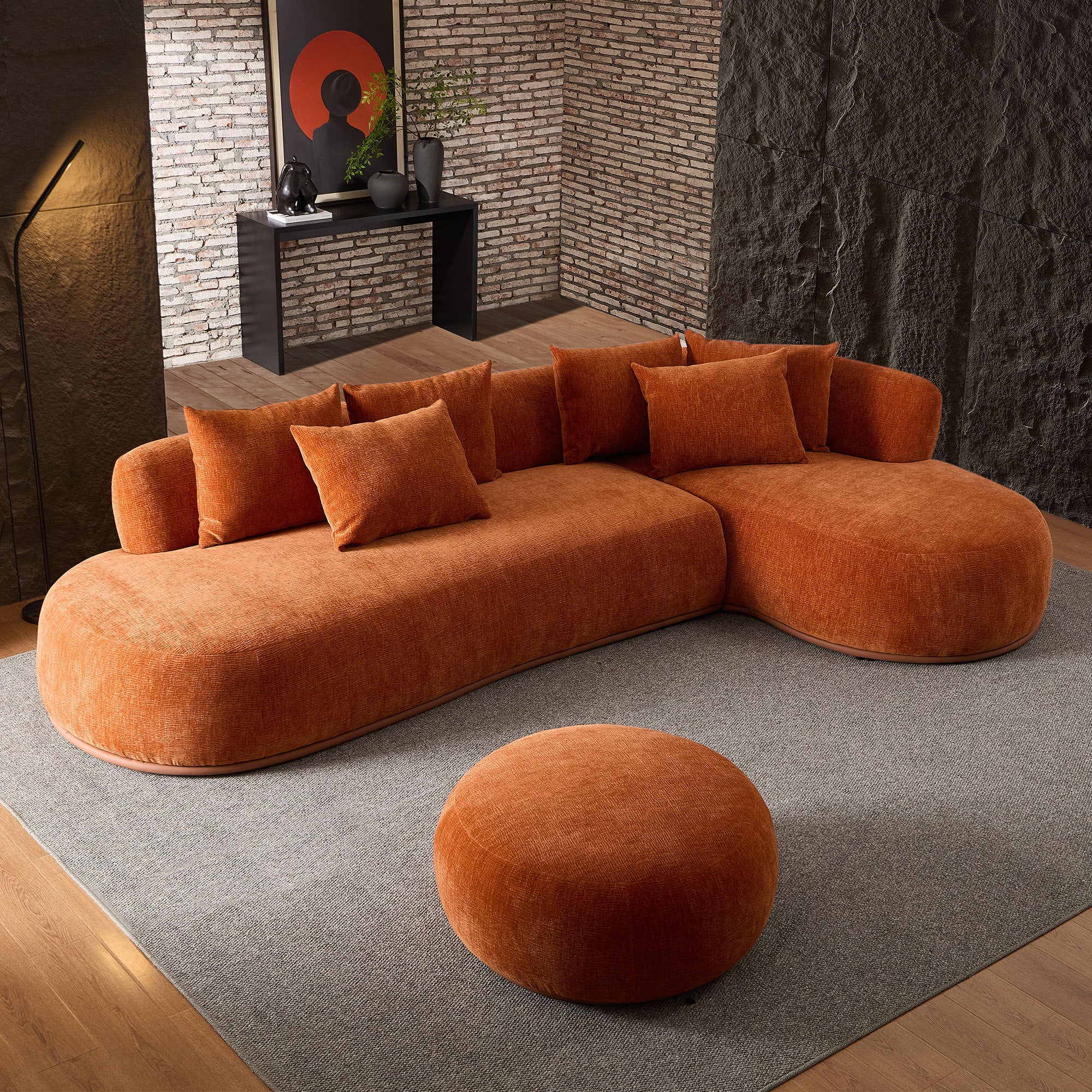 Curved 134.63'' orange sectional sofa with ottoman in a stylish interior, showcasing plush cushions and soft fabric texture.