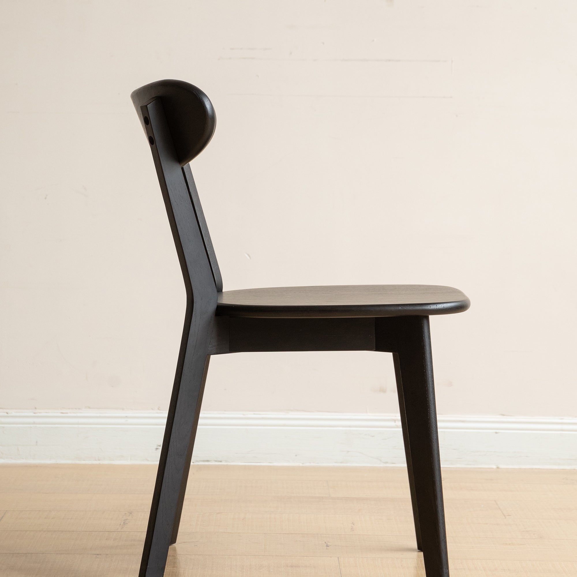 Side profile of Solid Oak Dining Chair in black, highlighting its ergonomic seat and angled legs for stability and comfort.