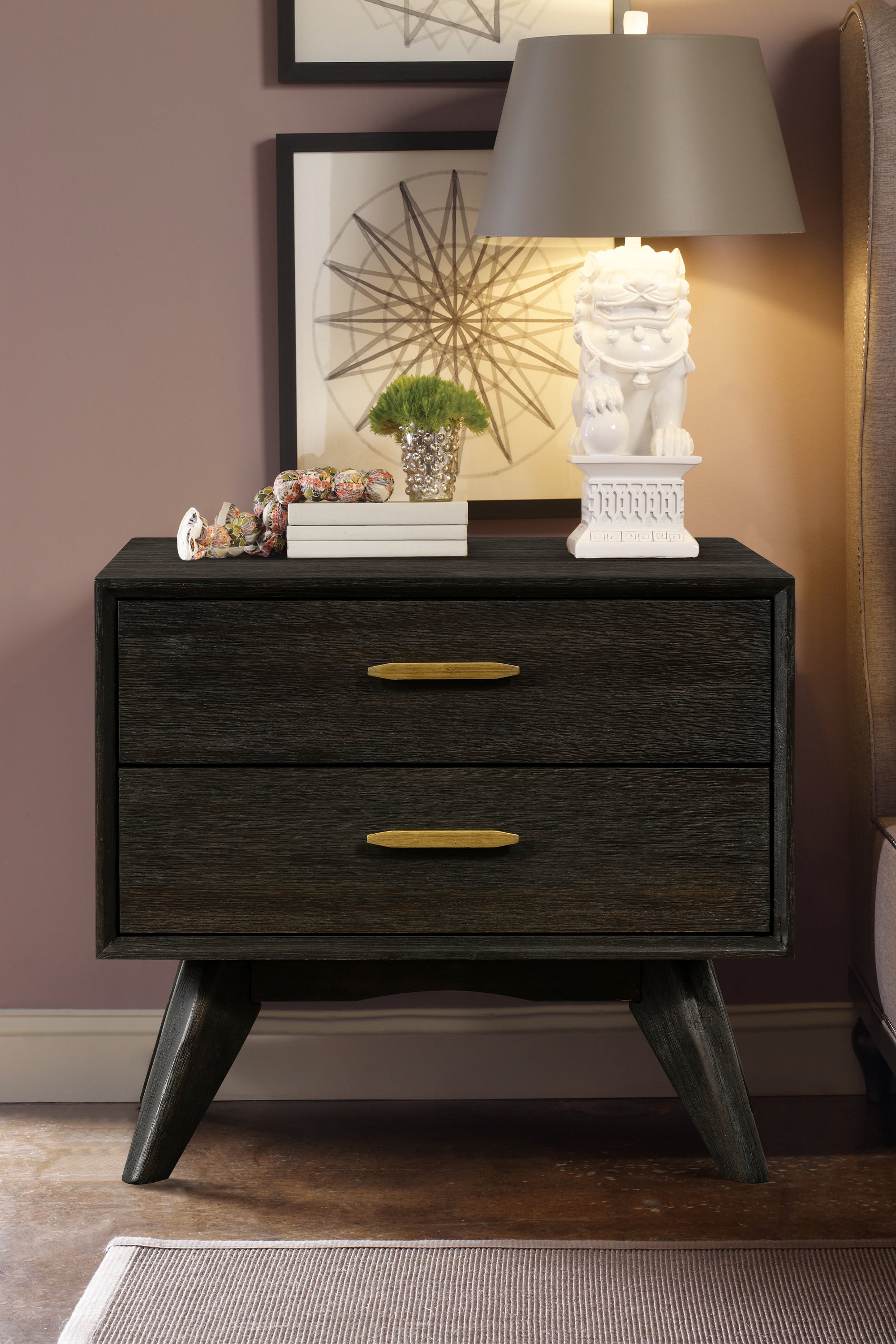 Mid-century modern nightstand in dark acacia wood with two drawers, gold hardware, and tapered legs.