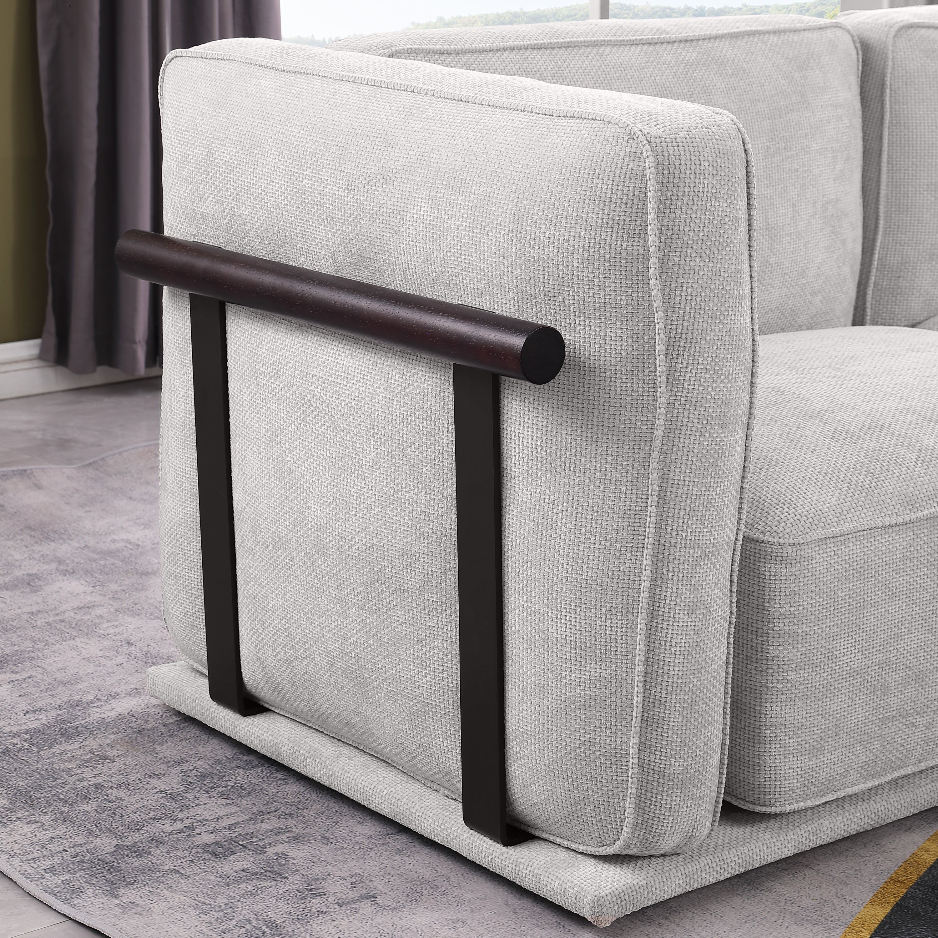 Side view of modular fabric sofa armrest with dark wood and metal support, blending modern aesthetics with functional design.