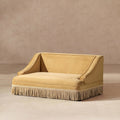 Gold yellow performance velvet pet sofa with elegant sloped arms and a decorative cream fringe skirt base.