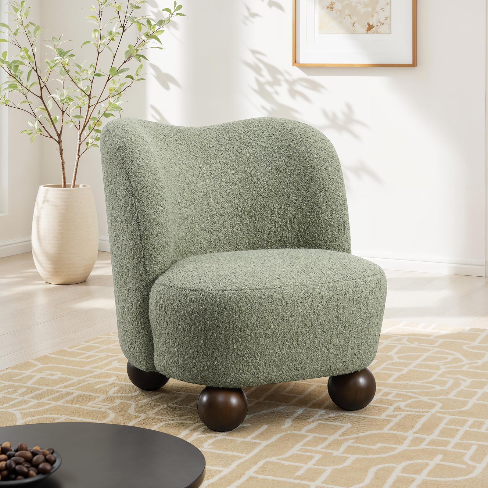 Green boucle chair with ball feet in modern living room. Stylish accent seating with curved back and soft texture for cozy interiors.