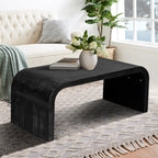 Farmhouse Crafts Coffee Table in black with Art Deco curves, featured in a bright living space with textured rug and cream sofa.