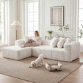 Modern off-white, L-shaped sectional sofa with plush, tufted upholstery and deep seating in a bright, airy living room.