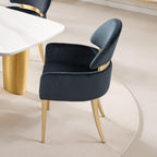 Contemporary black dining arm chair with matte gold stainless steel legs beside a white marble table, perfect for modern interiors.