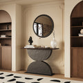 Modern console table with a wooden top and sculptural dark gray base featuring two hammered-texture semi-circles.