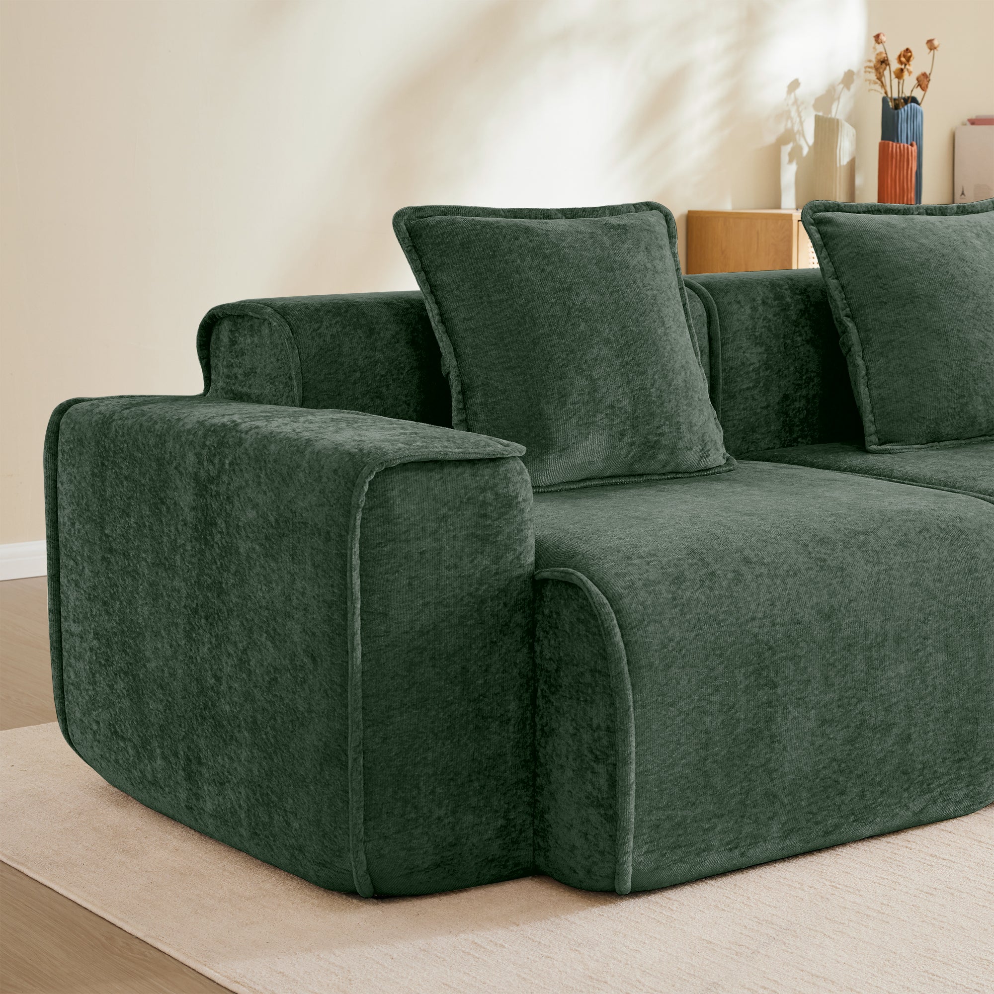 Detail of left armrest and pillow on modular velvet sectional sofa, showcasing plush comfort and French piping finish.