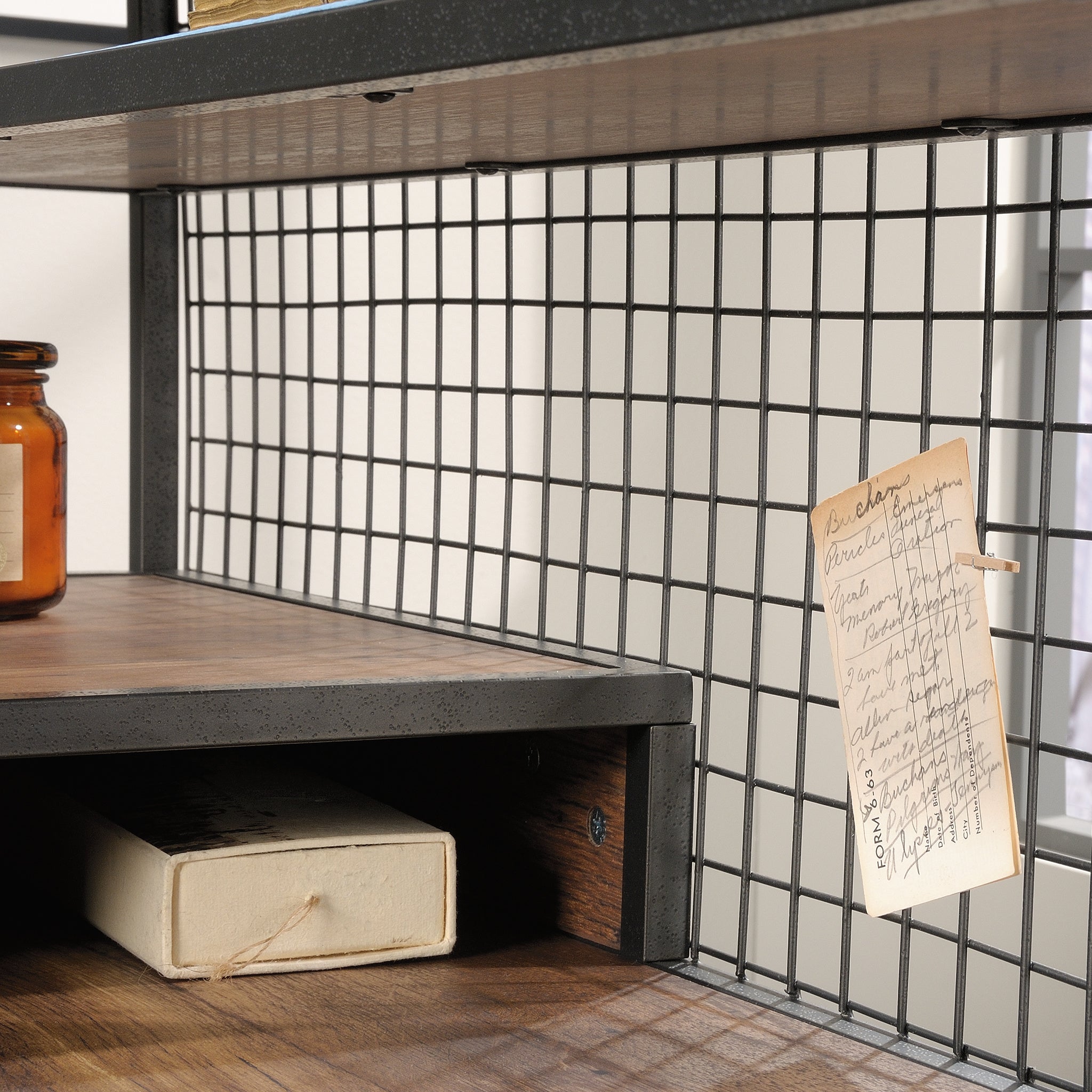 Grid-style metal back panel of L-shaped computer desk, brown finish, used for pinning notes and enhancing industrial design aesthetic.