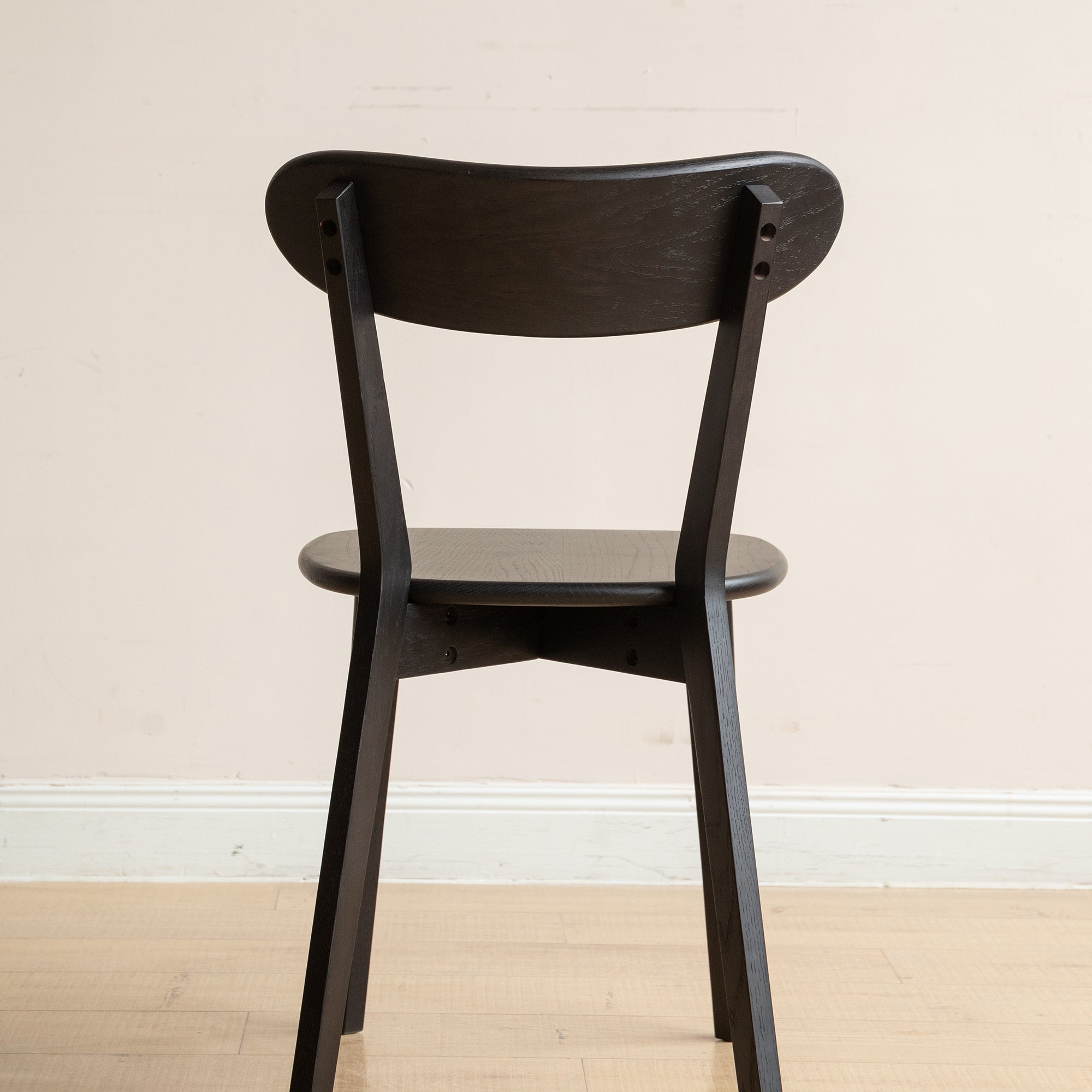 Back view of black Solid Oak Dining Chair showcasing its sturdy frame and smooth wood grain texture.