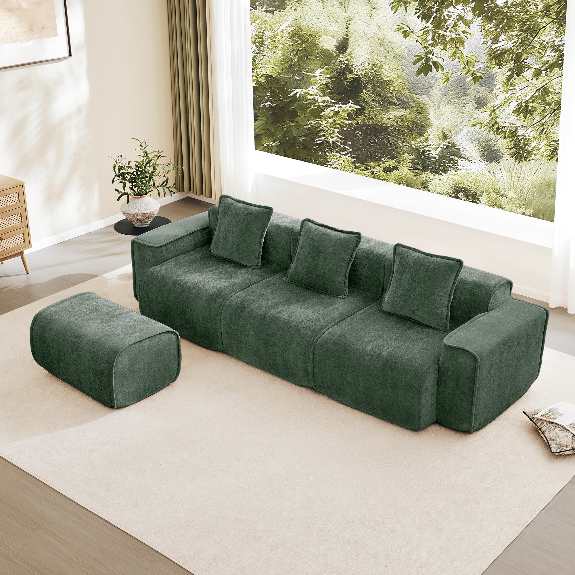 Modular Velvet Sofa - 3 Seat L Shape in green velvet with movable ottoman, placed in a modern living room with large window view.