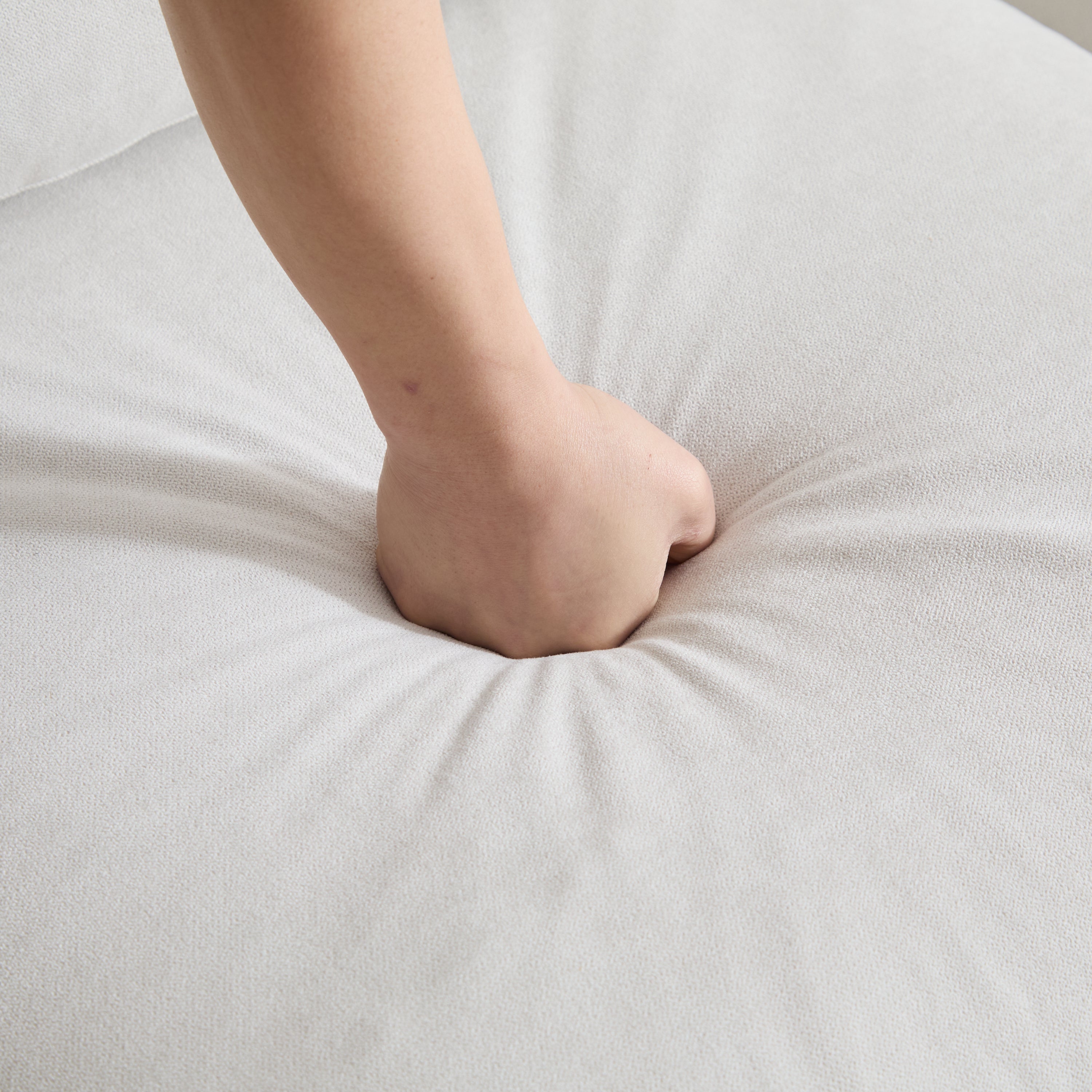 Hand pressing into the seat cushion of the 99 in. 4-piece L shaped modular sectional sofa, demonstrating its soft and supportive foam.