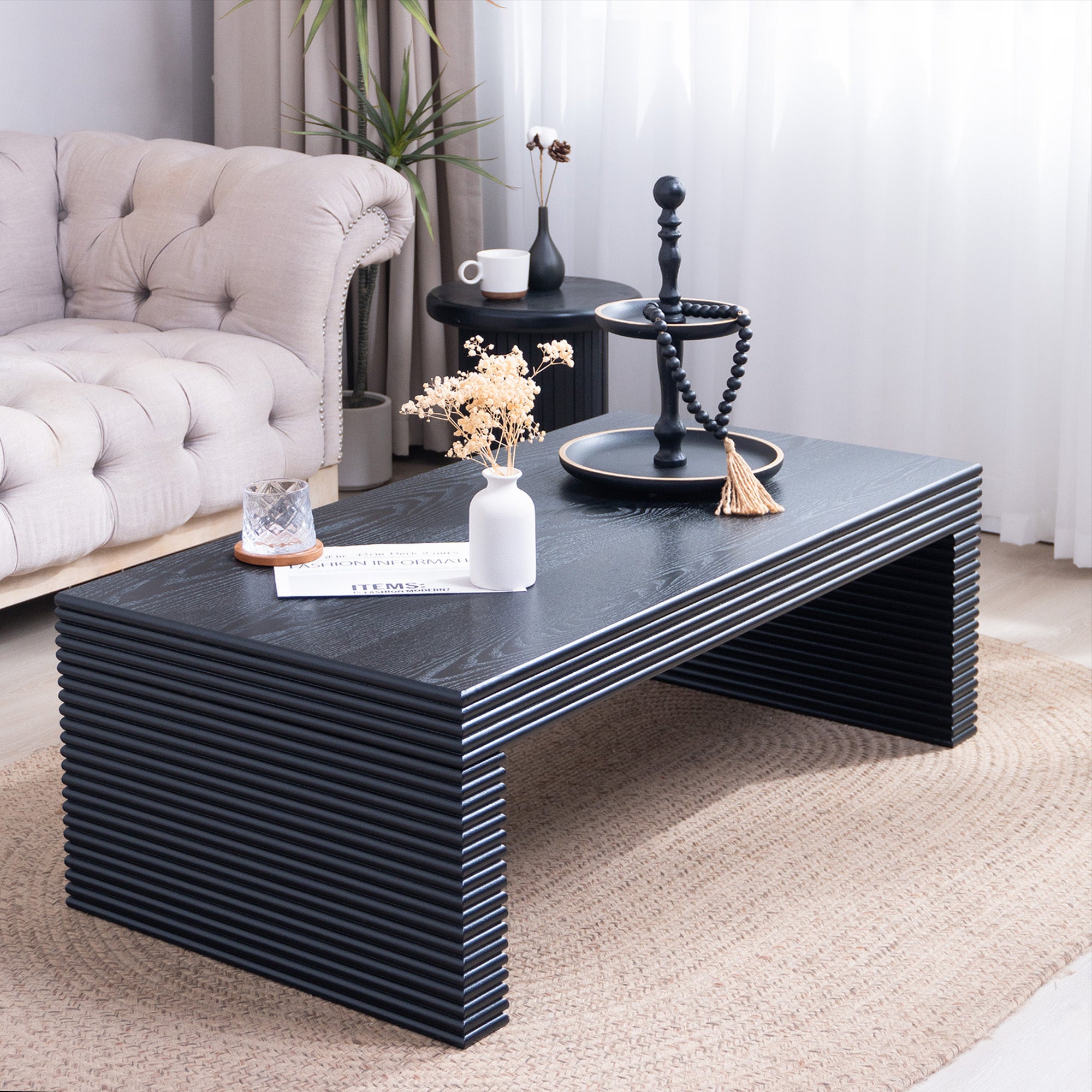 Modern black ribbed coffee table styled in a living room setting, showcasing its sleek rectangular shape and textured finish.