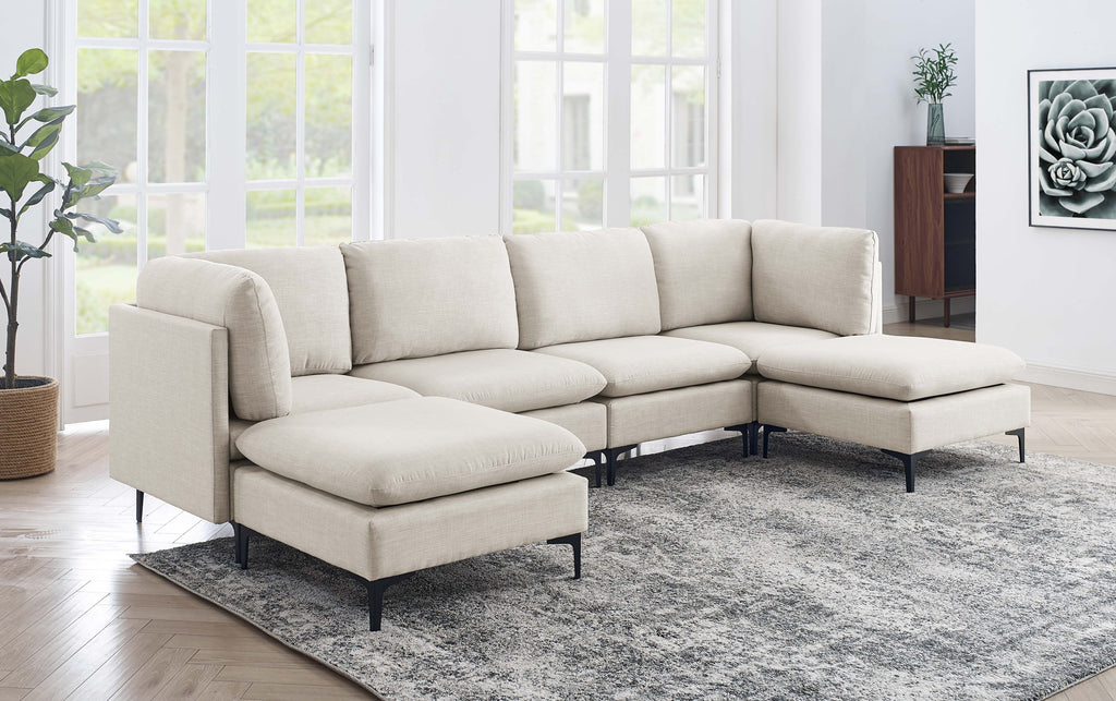 Beige linen modular sectional sofa with dual chaises and black metal legs in a bright, modern living room.