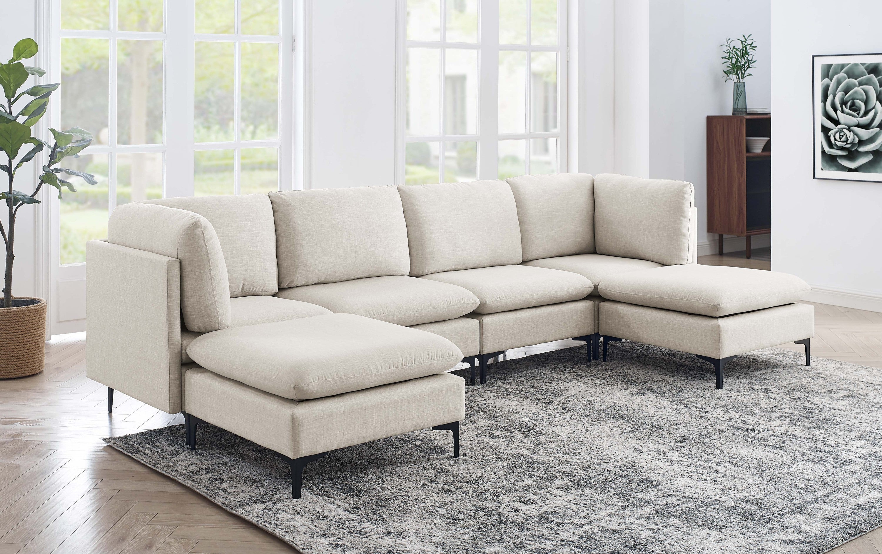 Beige linen modular sectional sofa with dual chaises and black metal legs in a bright, modern living room.