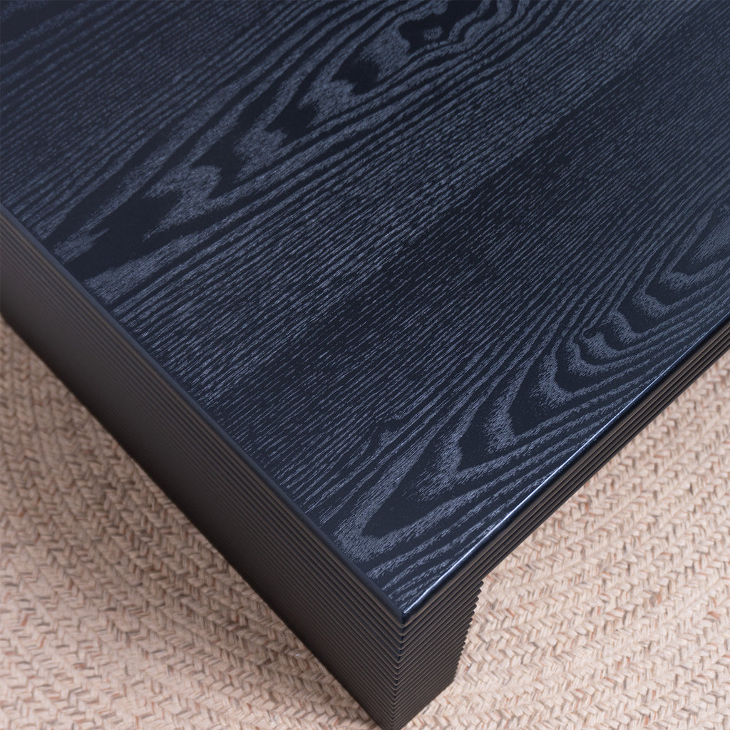 Detailed view of the black wood grain tabletop on the modern ribbed coffee table, showcasing its natural texture and finish.