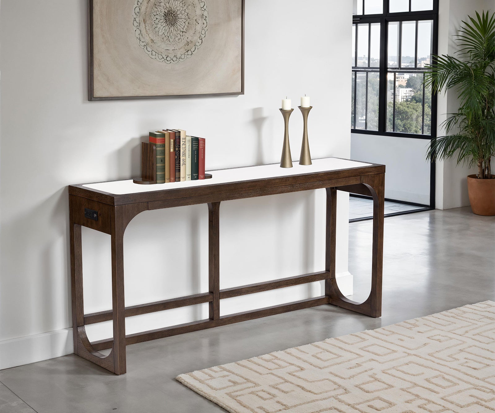 Transitional sofa table with USB port in dark walnut finish placed against a white wall in a modern living room. Features sleek engineered wood design.