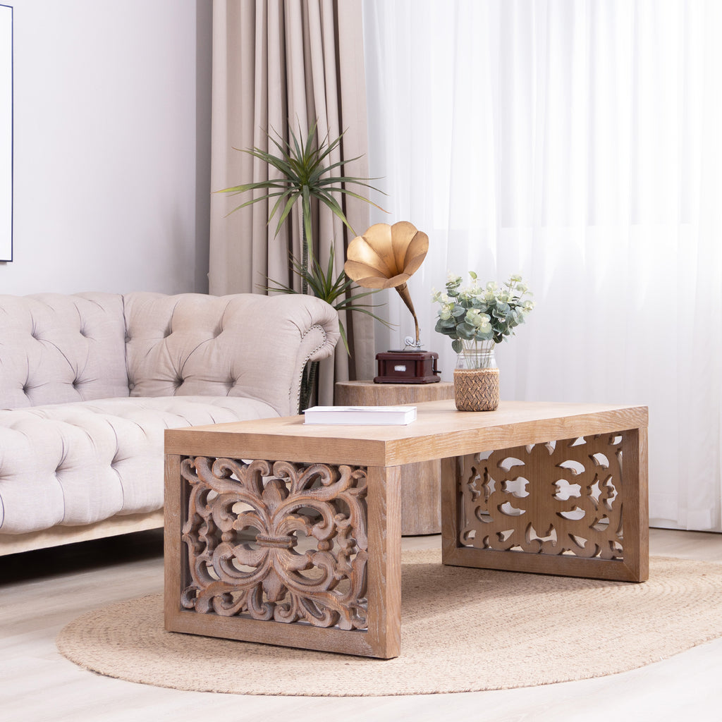 Handcrafted rustic wood coffee table with carved side panels placed in a modern living room, enhancing the natural decor theme.