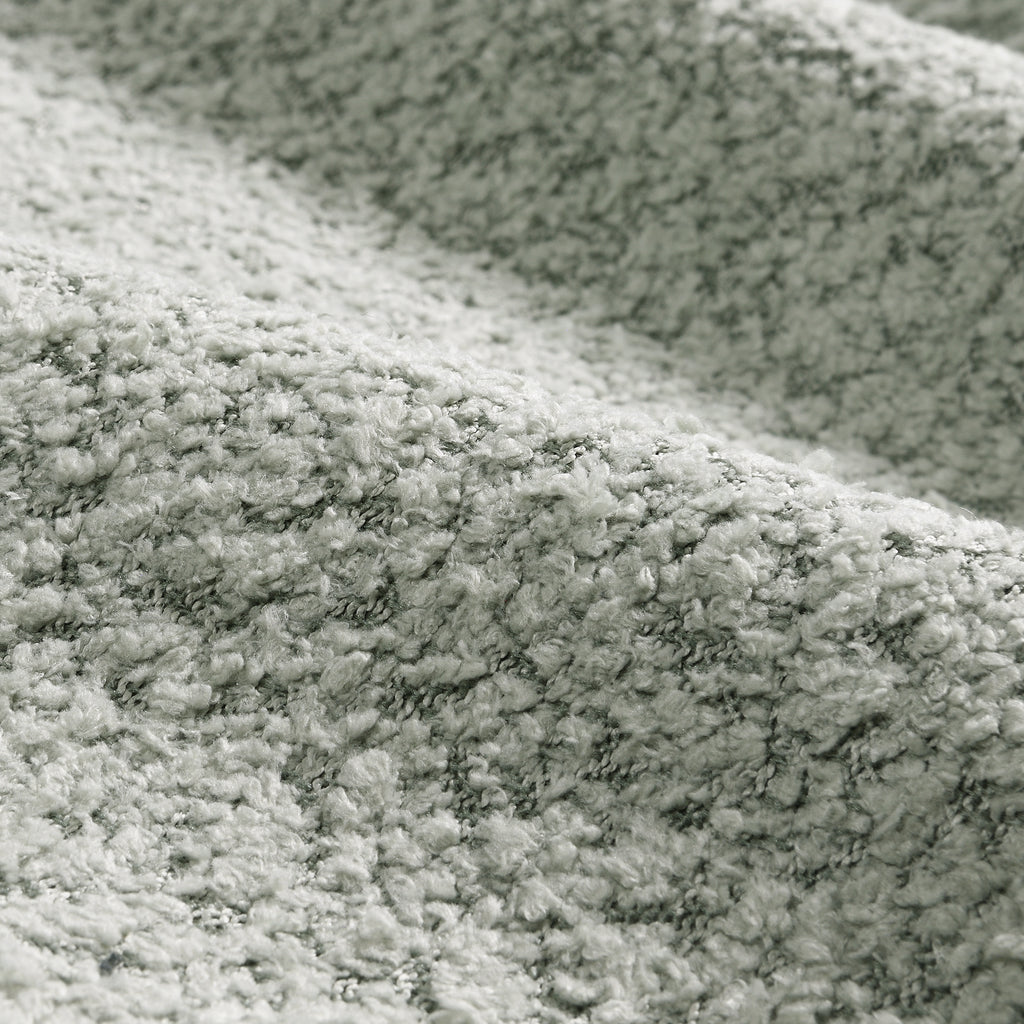 Close-up texture of boucle fabric used on the modular sectional sofa with ottoman, emphasizing softness and durability.
