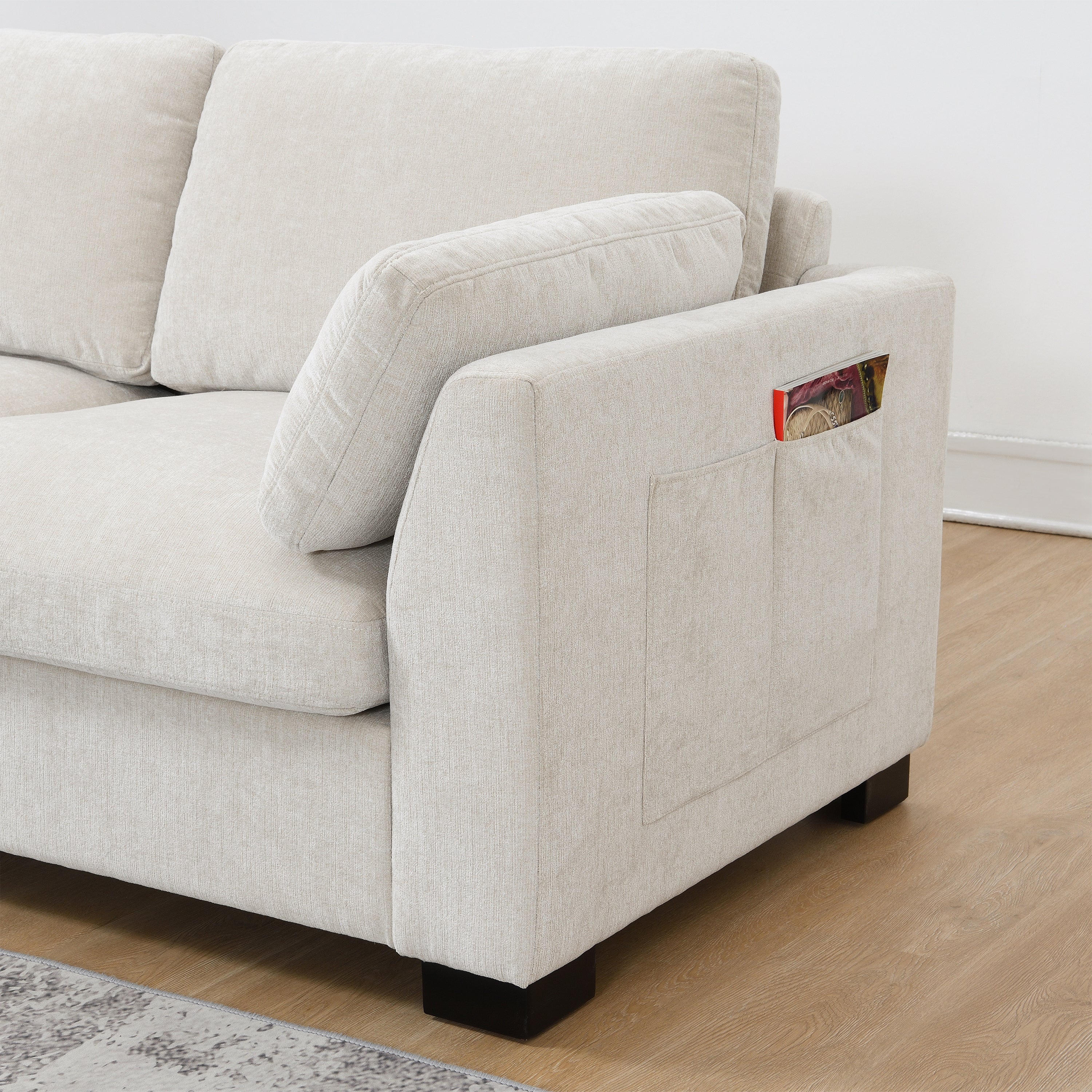 Side storage pocket on modular sectional sofa armrest, holding a book for convenient access.
