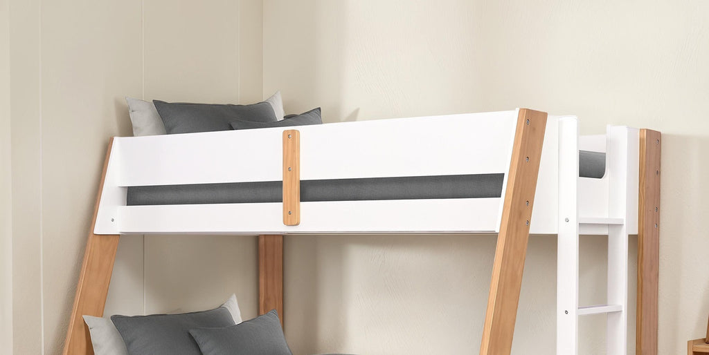 Close-up of the upper bunk on a twin over full bunk bed with natural finish, highlighting safety rails and wood details.
