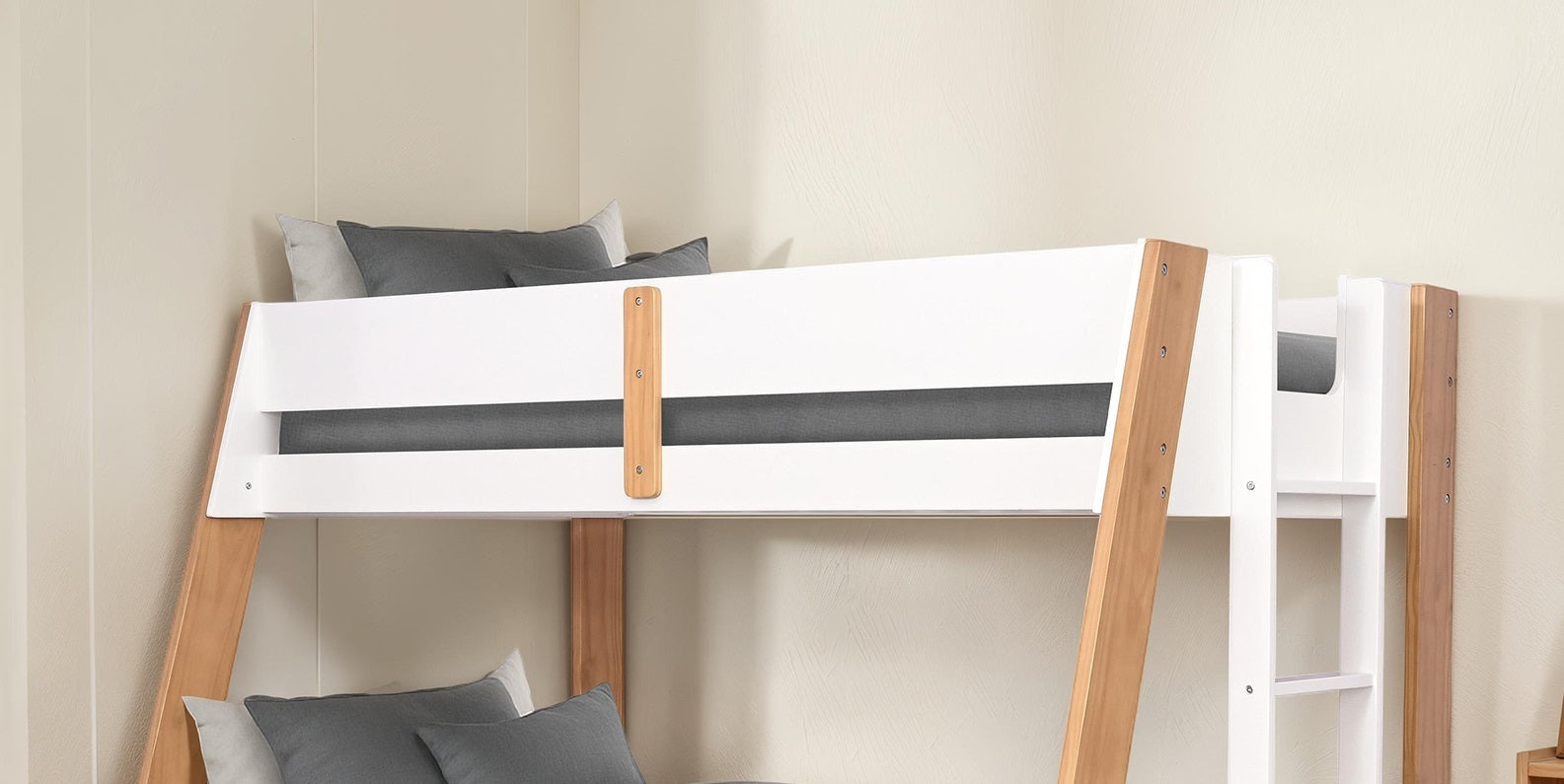 Close-up of the upper bunk on a twin over full bunk bed with natural finish, highlighting safety rails and wood details.