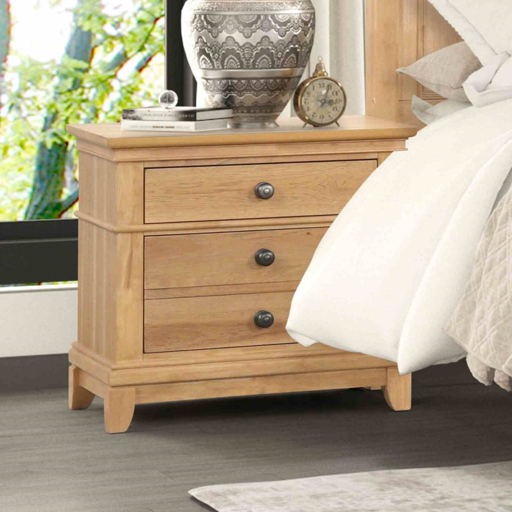 Farmhouse Oak Nightstand beside bed in modern farmhouse bedroom. 3-drawer wood nightstand with rustic charm and easy assembly.