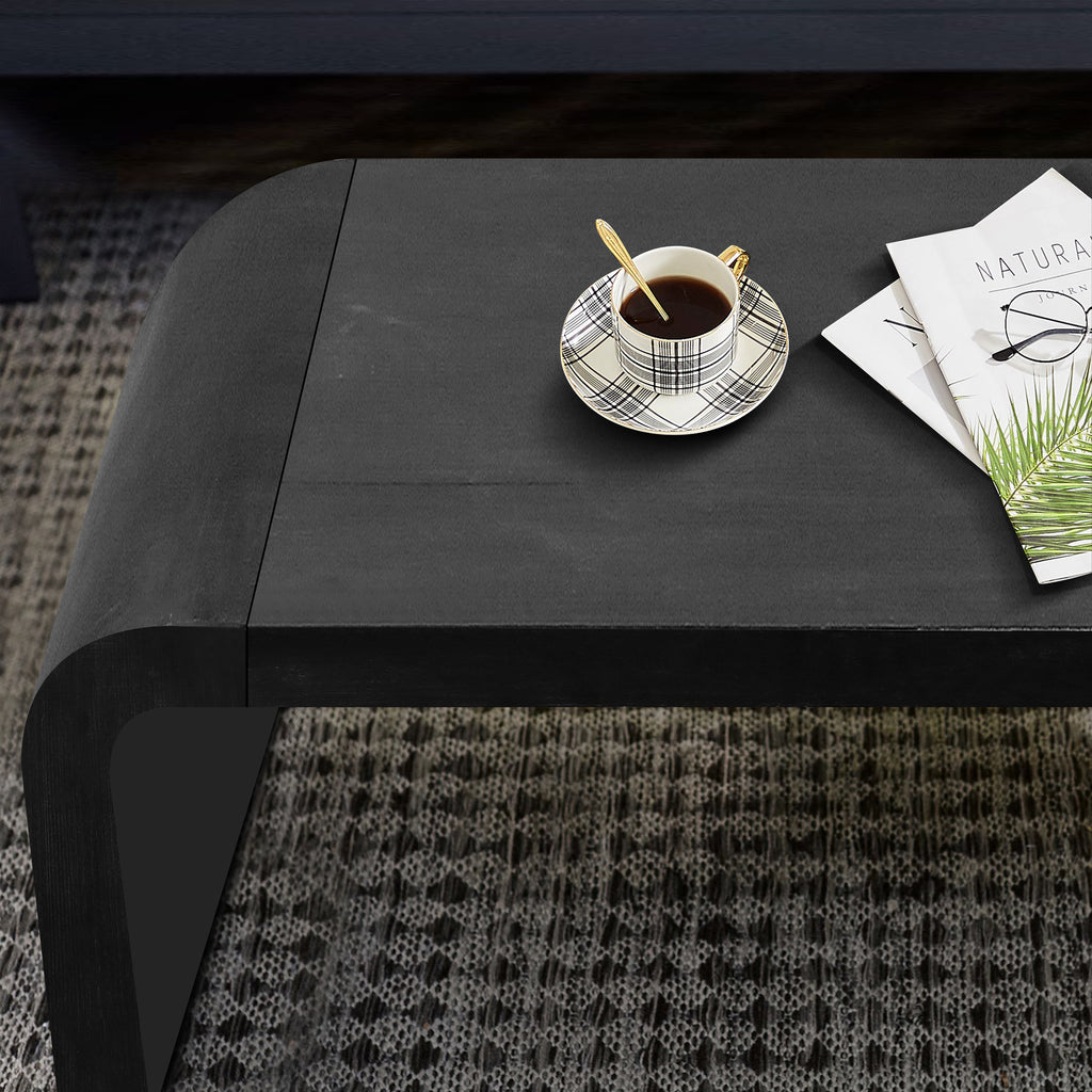 Close-up of the Vintage Farmhouse Coffee Table top with coffee cup and magazine, showcasing smooth black finish and curved design.