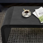 Close-up of the Vintage Farmhouse Coffee Table top with coffee cup and magazine, showcasing smooth black finish and curved design.