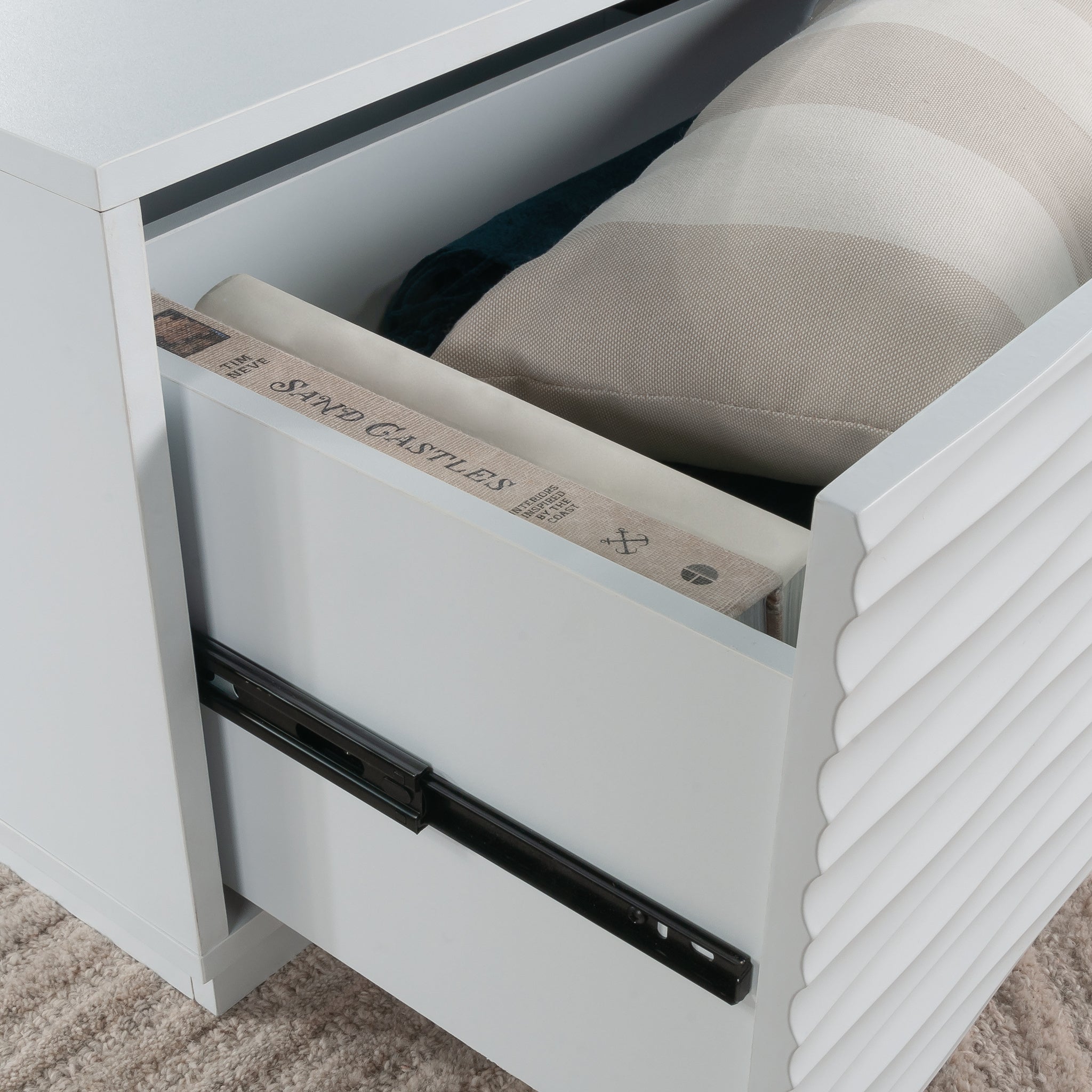 Interior drawer view of the white coffee table showing ample storage space for books and cushions in a modern coastal design.