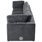 Side view of modular sofa with storage and charging ports, featuring built-in Bluetooth speaker and plush cushions in dark grey fabric.