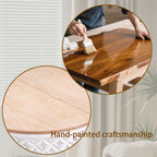 Close-up of hand-painted craftsmanship on the natural wood top of a round coffee table with white carved base, showcasing artisanal detail.